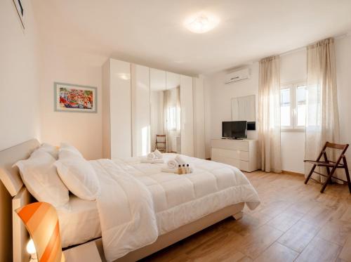 a white bedroom with a large bed and a television at Casa Tino Panorama Skyline in Polignano a Mare