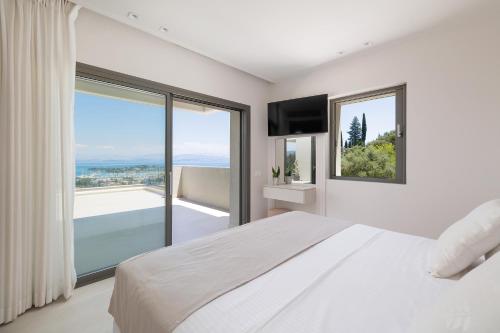 a bedroom with a white bed and a large window at Villa Eleni Di Mare in Kontokali