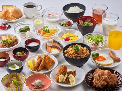 a table with many bowls of food on it at Dormy Inn Hiroshima in Hiroshima