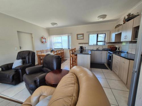 a living room with a couch and a kitchen at Sea side cottage in Stilbaai