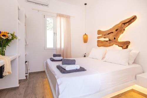 a bedroom with a white bed with a wooden headboard at Alexandra Suites - MYKONOS PORT in Mikonos