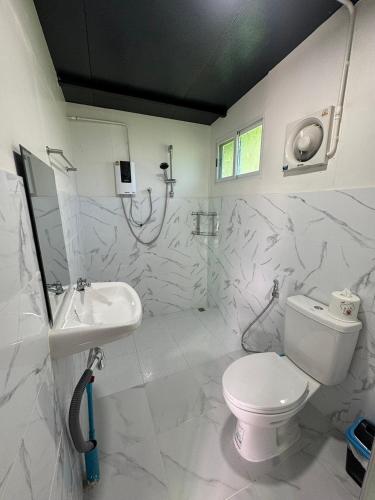 a white bathroom with a toilet and a sink at เหนือสะปัน in Ban Huai Ti