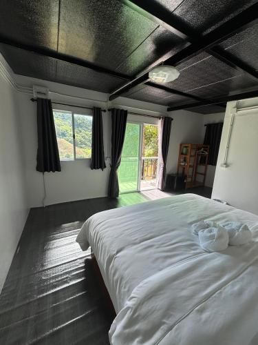 a bedroom with a large white bed and a window at เหนือสะปัน in Ban Huai Ti