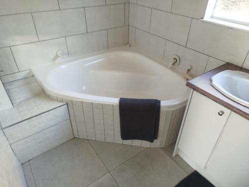 a white bath tub in a bathroom with a sink at NAMOLEKA House- Bloemfontein in Bloemfontein