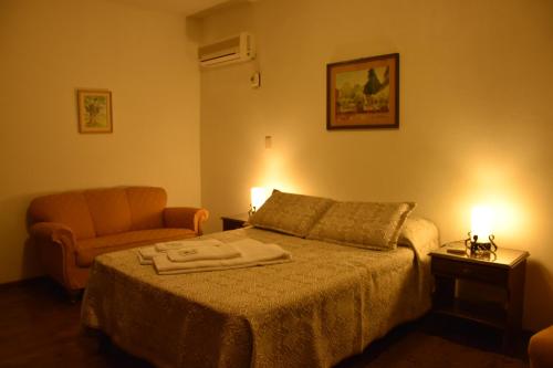 a bedroom with a bed and a chair and two lamps at SUIZO Hotel in Colonia Suiza