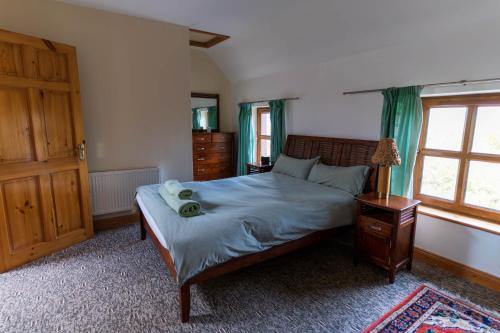 a bedroom with a bed and a dresser and a window at Stonechat Cottage - Portmagee in Portmagee