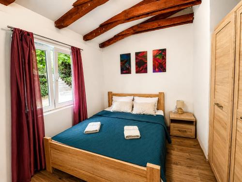 a bedroom with a bed with blue sheets and a window at Villa Sunset, Dobrota in Dobrota