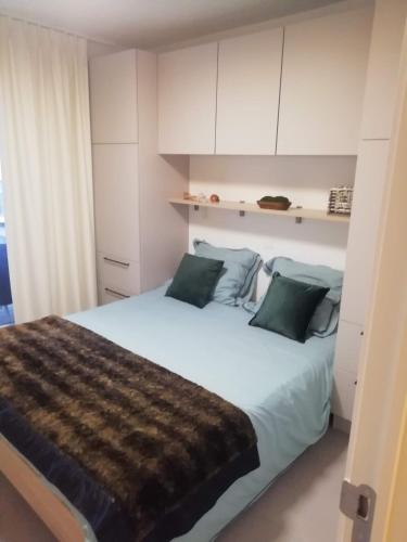 a bedroom with a bed with white cabinets and green pillows at Sailors' Park Villa Zephir in Nieuwpoort