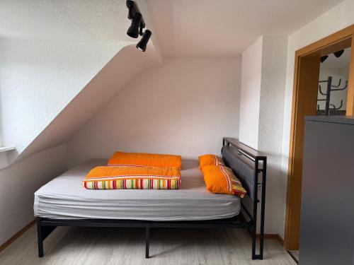 ein Bett mit orangefarbenen Kissen auf einem Dachboden in der Unterkunft MaVelo in Düren - Eifel