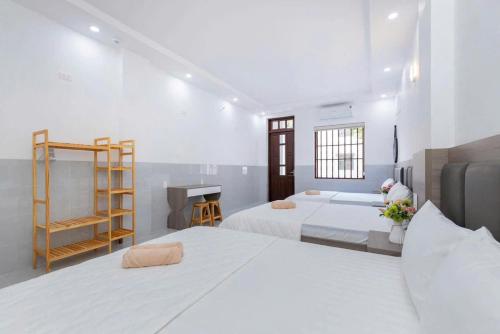 a white bedroom with two beds and a fireplace at Sói Homestay B10 HQL in Xã Thang Tam