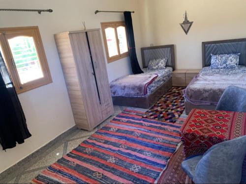 a room with two beds and a rug at Tinejdad Auberge in Tinejdad