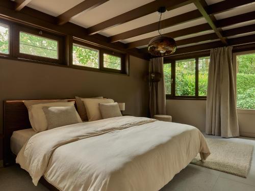 a bedroom with a large white bed with windows at Yasu Stay Sonnevijver Rekem in Lanaken