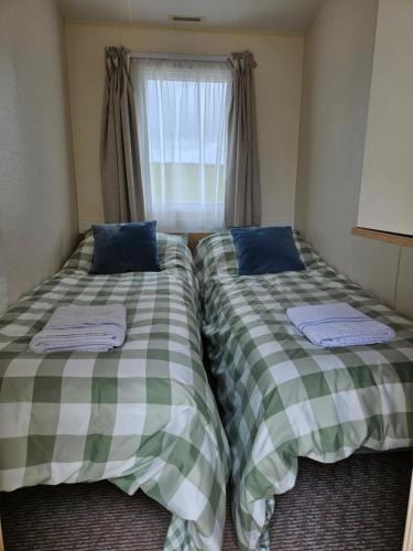two beds in a small room with a window at Manderley Caravan in Newquay Bay Resort