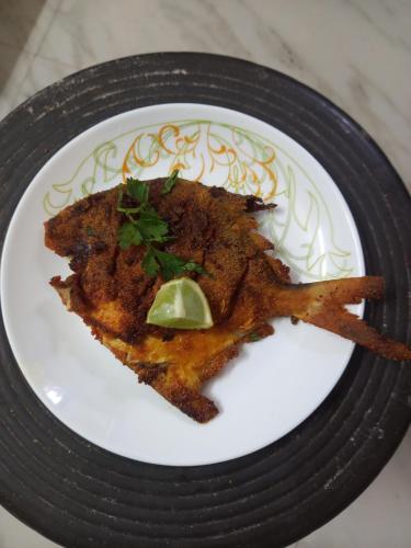 a white plate with a piece of fish with a lime at Sanvi Resort Malvan in Malvan