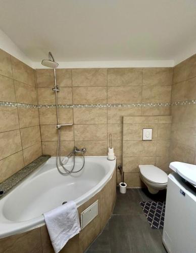a bathroom with a tub and a toilet and a sink at Modern apartment with space for 6 in Weißenfels