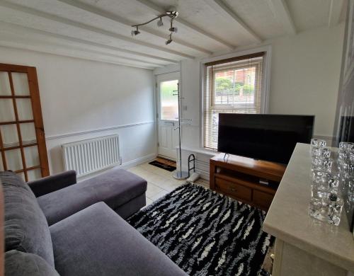 a living room with a couch and a flat screen tv at Carisbrooke Mill Cottage in Newport