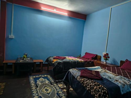 a room with three beds and a blue wall at Laxmi Homestay in Kalimpong