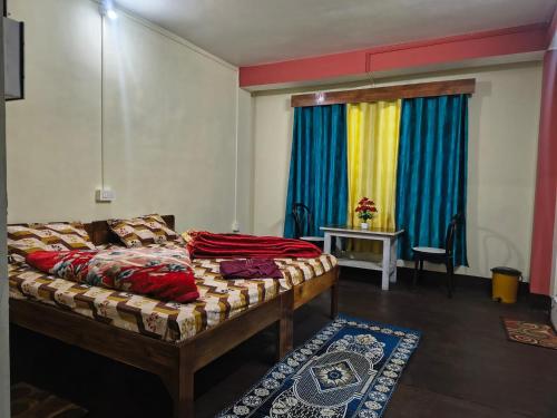 a bedroom with a bed and a table and a window at Laxmi Homestay in Kalimpong
