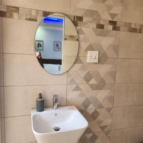 a bathroom with a sink and a mirror at Cozy & Modern Apartment -Self Catering in Pretoria