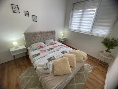 a bedroom with a bed with two tables and a window at Fenix Apartman II in Zaječar