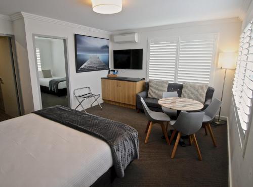 a hotel room with a bed and a table and chairs at Quays Hotel in Batemans Bay