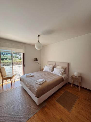 a bedroom with a bed and a chair and a window at Descanso, Mar & Conforto in Esposende