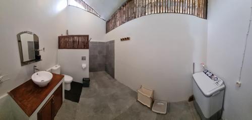 a bathroom with a sink and a toilet and a mirror at Valhalla Mentawai in Katiet