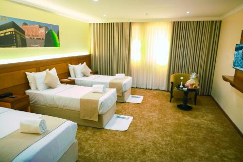 a hotel room with two beds and a television at Bab ALMultazam Concorde Hotel in Mecca