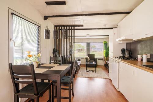 a kitchen and dining room with a table and chairs at Knus houten huisje bij het bos in Anloo