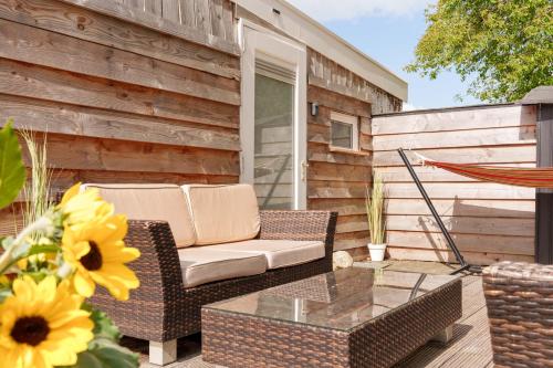 a patio with a couch and a glass table at Knus houten huisje bij het bos in Anloo
