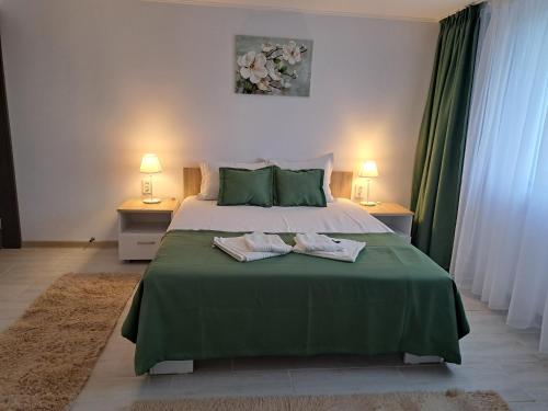 a bedroom with a large green bed with two towels on it at CASA ROTARU in 2 Mai