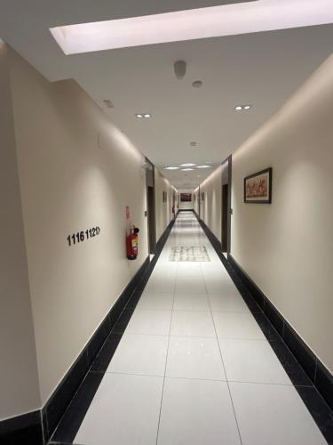 a long hallway with white walls and a white tile floor at Address Sharurah Hotel in Sharurah