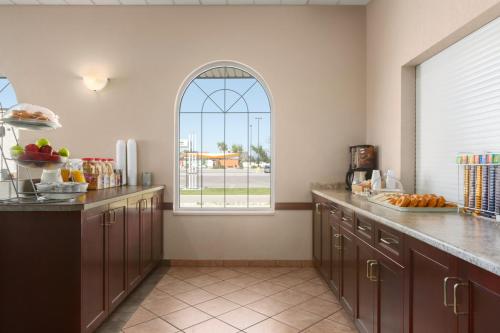 a kitchen with an arched window and wooden cabinets at Days Inn & Suites by Wyndham Winkler in Winkler