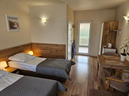 a bedroom with two beds and a table and a desk at Piotruś Pan in Niechorze