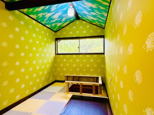 a room with a yellow wall with a table in it at チェックアウトは11時コテージそら豆ん家 in Nasu