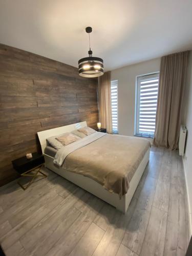 a bedroom with a large bed and a wooden wall at Apartament AquaTower, Aquapark Reda in Reda