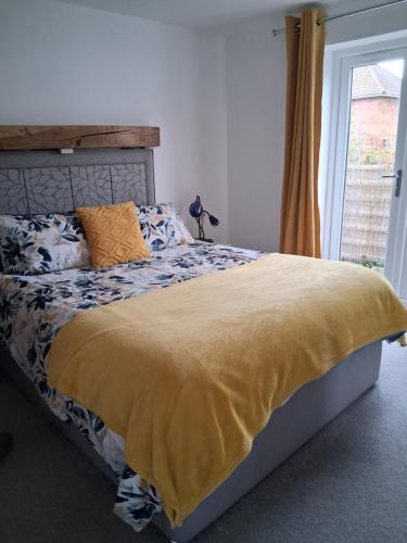 a bedroom with a bed with a yellow blanket and a window at Secret Bungalow in Warsop