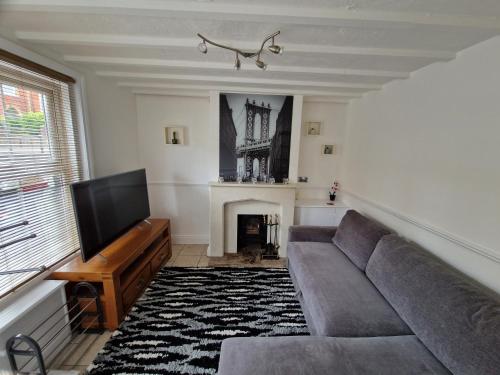 a living room with a couch and a tv at Carisbrooke Mill Cottage in Newport