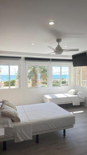 a white room with two beds and windows at El Chalecito De Alicante in El Campello