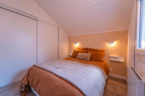 ein Schlafzimmer mit einem Bett mit orangefarbenen Laken und einem Fenster in der Unterkunft Nid face au MontBlanc - 55m2 de charme in Sallanches