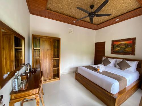a bedroom with a bed and a ceiling fan at Raka Rai House in Ubud