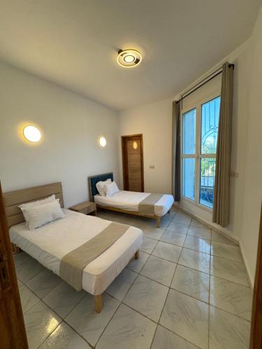 a bedroom with two beds and a large window at Villa Pieds dans l eau entre Lagune et Montagne in Ghār al Milḩ