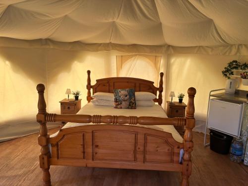 a bedroom with a wooden bed in a tent at Old Dairy Farm Glamping in Emsworth