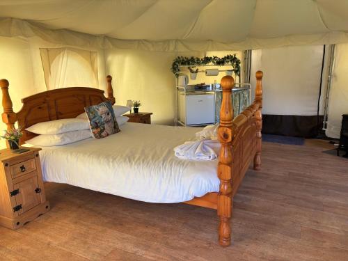 a bedroom with a wooden bed and a kitchen at Old Dairy Farm Glamping in Emsworth