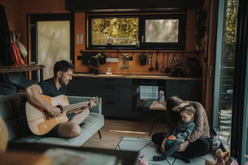 a man playing a guitar and a child sitting on a couch at Chalúpka na kopcu in Buchlovice