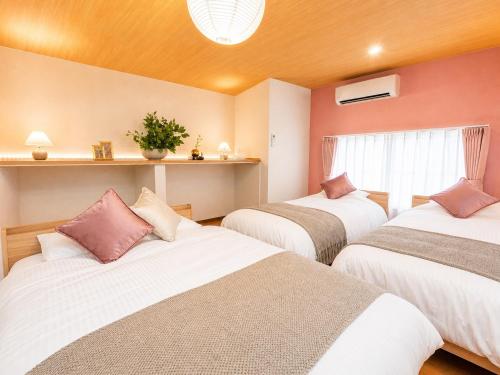 a room with three beds and a window at TOMOSHIBI Kurashiki Zen House Near Bikan Historical Quarter 美観地区近く 和モダン一棟貸し in Kurashiki