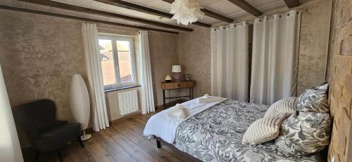 a bedroom with a bed and a chair and a window at Chez Denise in Eglingen