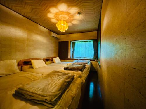 two twin beds in a room with a chandelier at コテージちゃ豆ん家 in Nasu