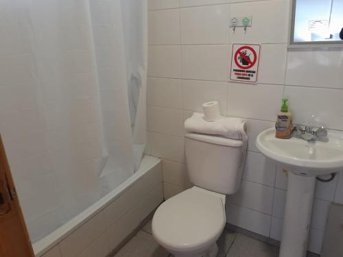 a white bathroom with a toilet and a sink at Alojamiento Punta Arenas in Punta Arenas