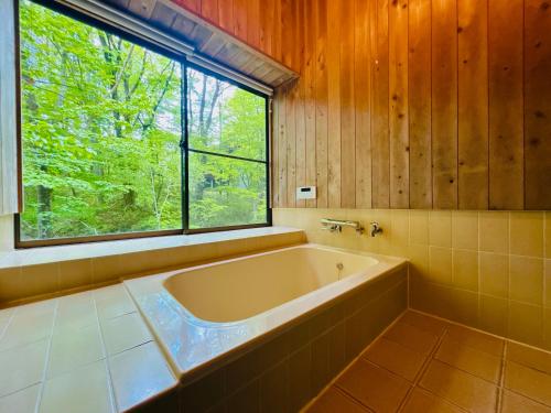 a bath tub in a bathroom with a window at コテージちゃ豆ん家 in Nasu